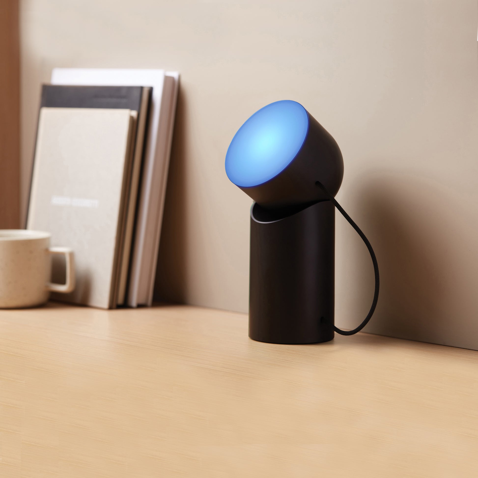 Lexon Orbe Zwart│Oplaadbare Tafellamp│art. LH88N│op bureau met blauw licht aan