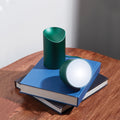 Lexon Orbe Donkergroen│Oplaadbare Tafellamp│art. LH88DG1│op stapel boeken met lamphoofd los naast basis