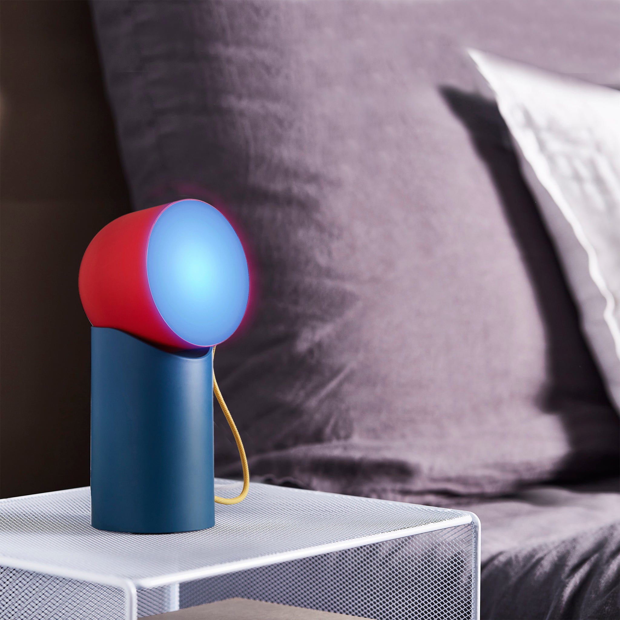 Lexon Orbe Duck Blue&Red│Oplaadbare Tafellamp│art. LH88DRY│op metalen nachtkastje met blauw licht aan