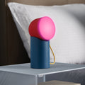Lexon Orbe Duck Blue&Red│Oplaadbare Tafellamp│art. LH88DRY│op metalen nachtkastje met roze licht aan