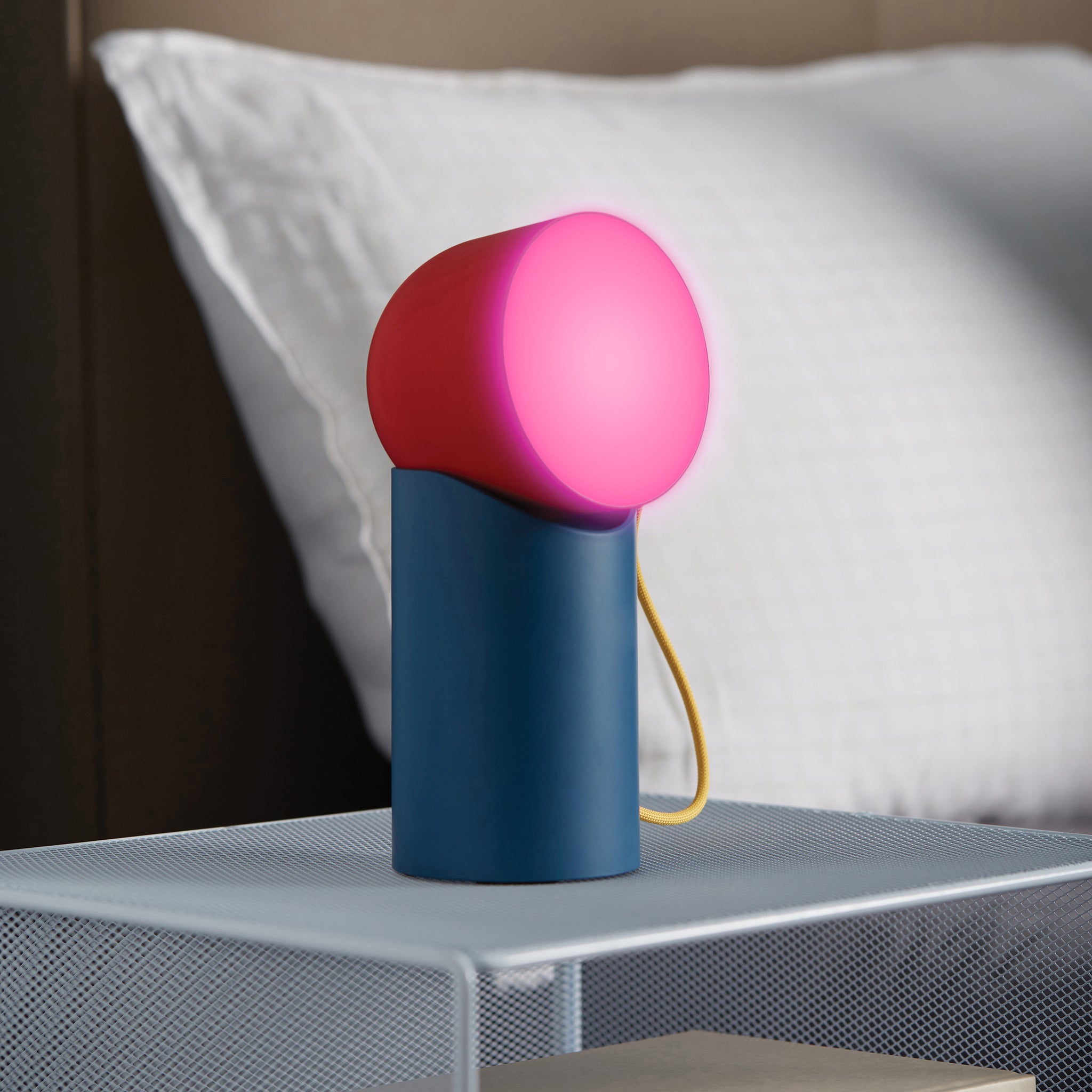 Lexon Orbe Duck Blue&Red│Oplaadbare Tafellamp│art. LH88DRY│op metalen nachtkastje met roze licht aan