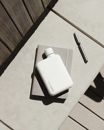Memobottle A Stainless steel Wit ligt met nototieboek op betonnen bankje.