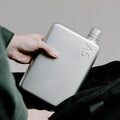 Memobottle A5 Platte Waterfles Satin in hand boven zwarte tas.