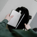 Man stopt Memobottle A5 Satin RVS in tas naast laptop.
