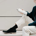 Man op betonnen bank houdt Memobottle Platte Waterfles Slim RVS Slim Satin in hand.