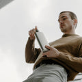 Onderaanzicht Memobottle Platte Waterfles Slim RVS Slim Satin in hand van man.