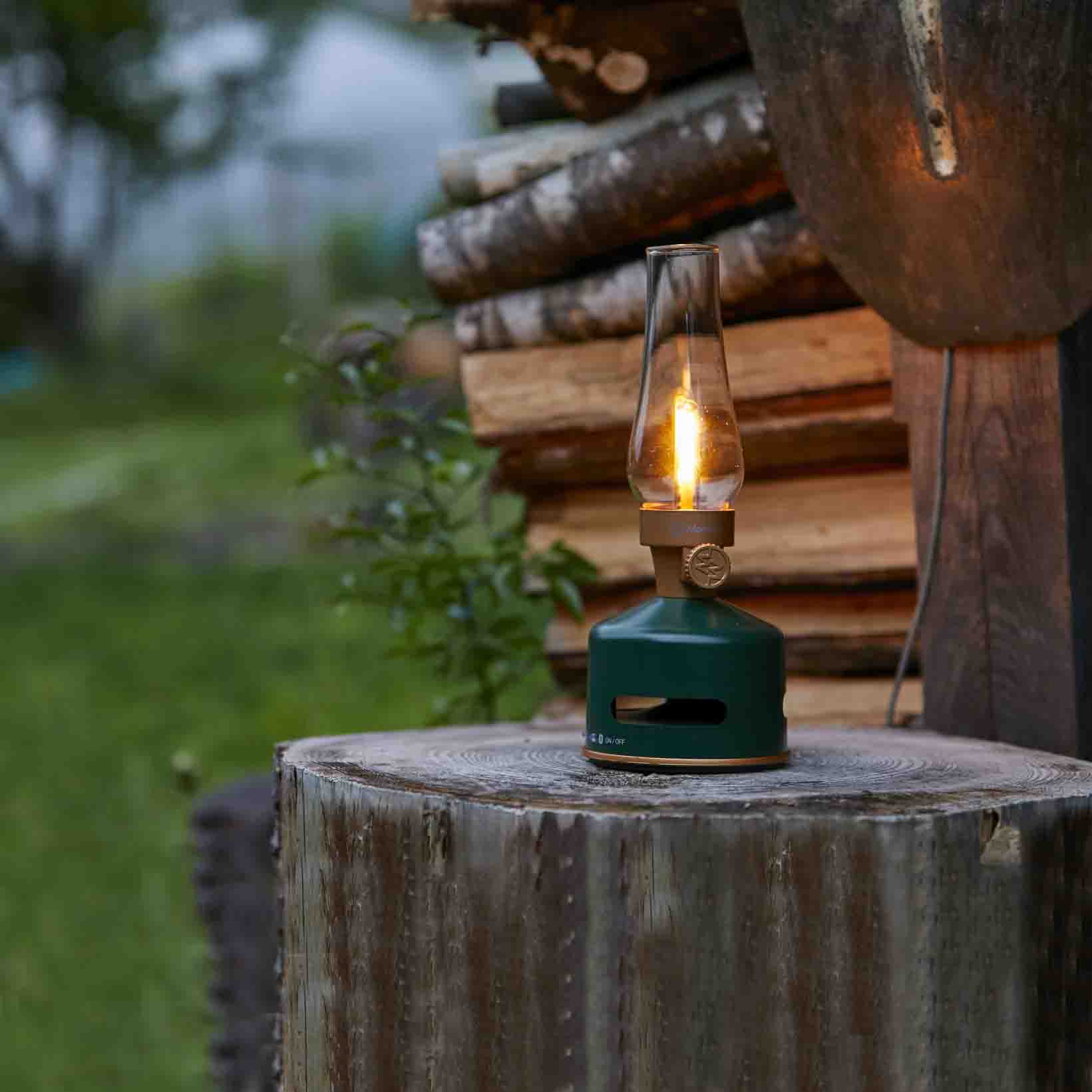 MoriMori LED Lantern & Bluetooth Speaker Original Green│Buitenverlichting Oplaadbaar│art. FLS-2101-DG│op houten blok in tuin met licht aan