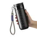 Dopper Travel Mug Blazing Black Large 400ml met Wrist Cord Sandy Black vastgehouden in hand van vrouw