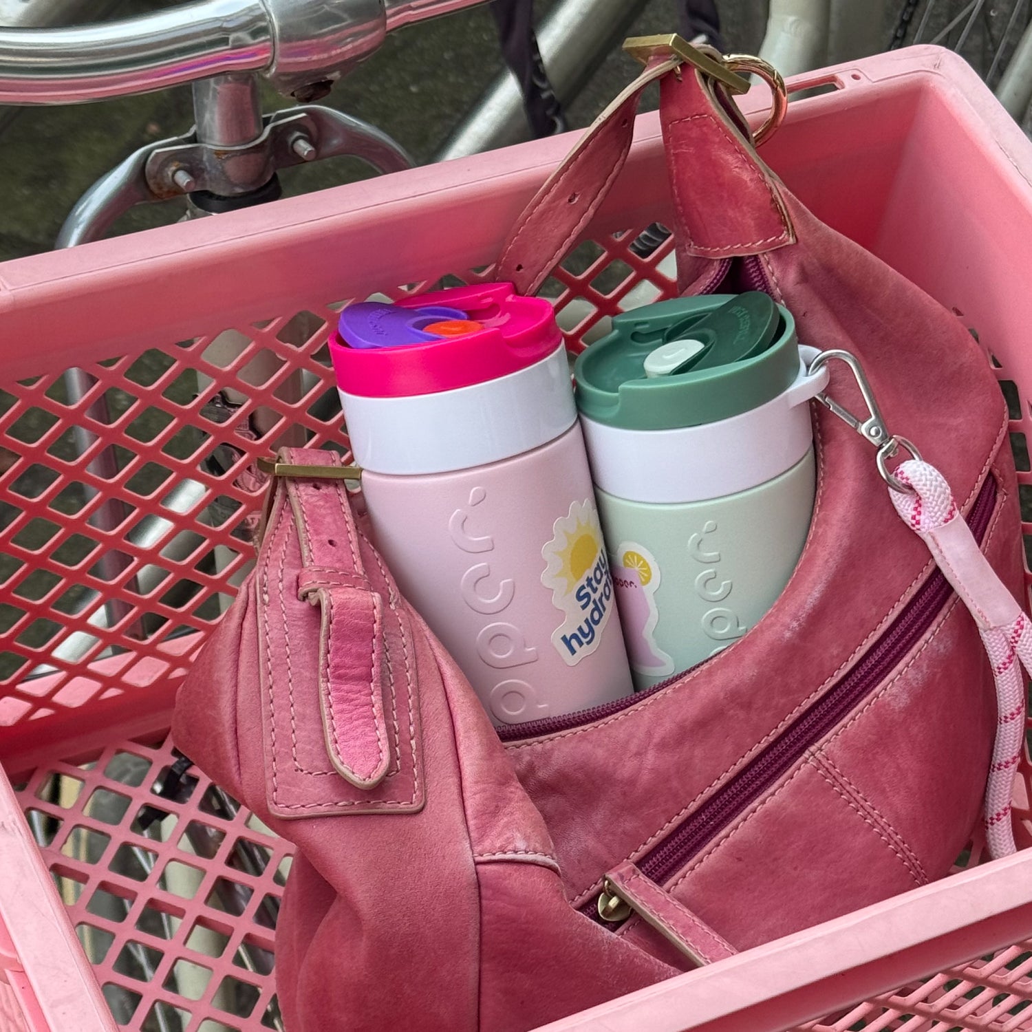 Travel Mug Berry Pink en Forest Green met Wrist Cord White & Cherry Pink in roze tas in fietsmand