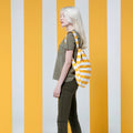 Vrouw met Notabag Golden Stripes rugzak voor geel/witte achtergrond