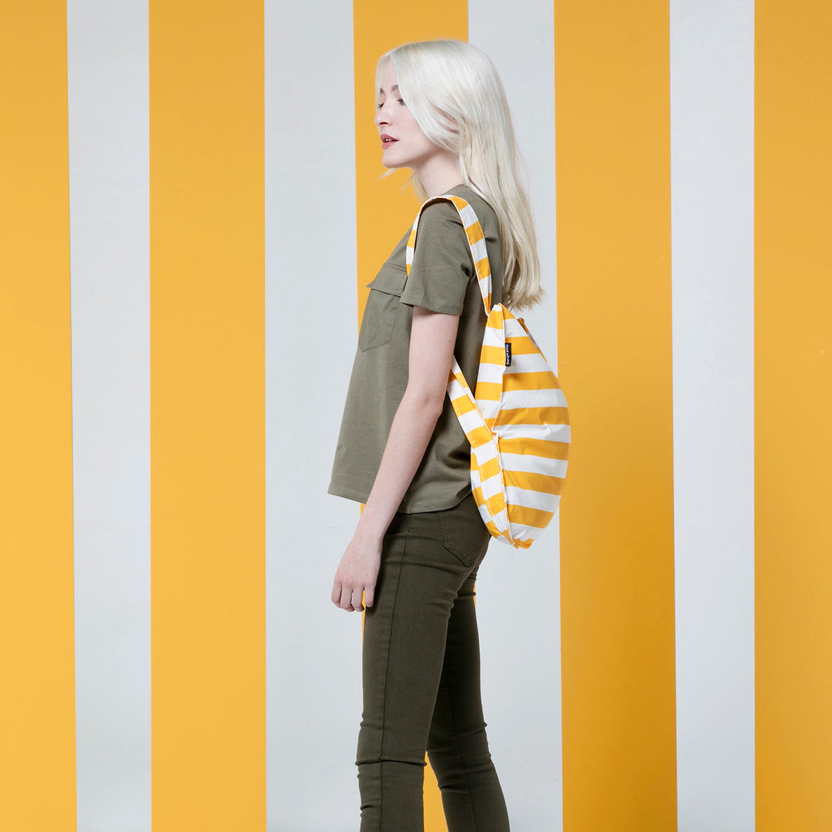 Vrouw met Notabag Golden Stripes rugzak voor geel/witte achtergrond