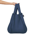 Navy blue Notabag as a shopper bag held in the hand