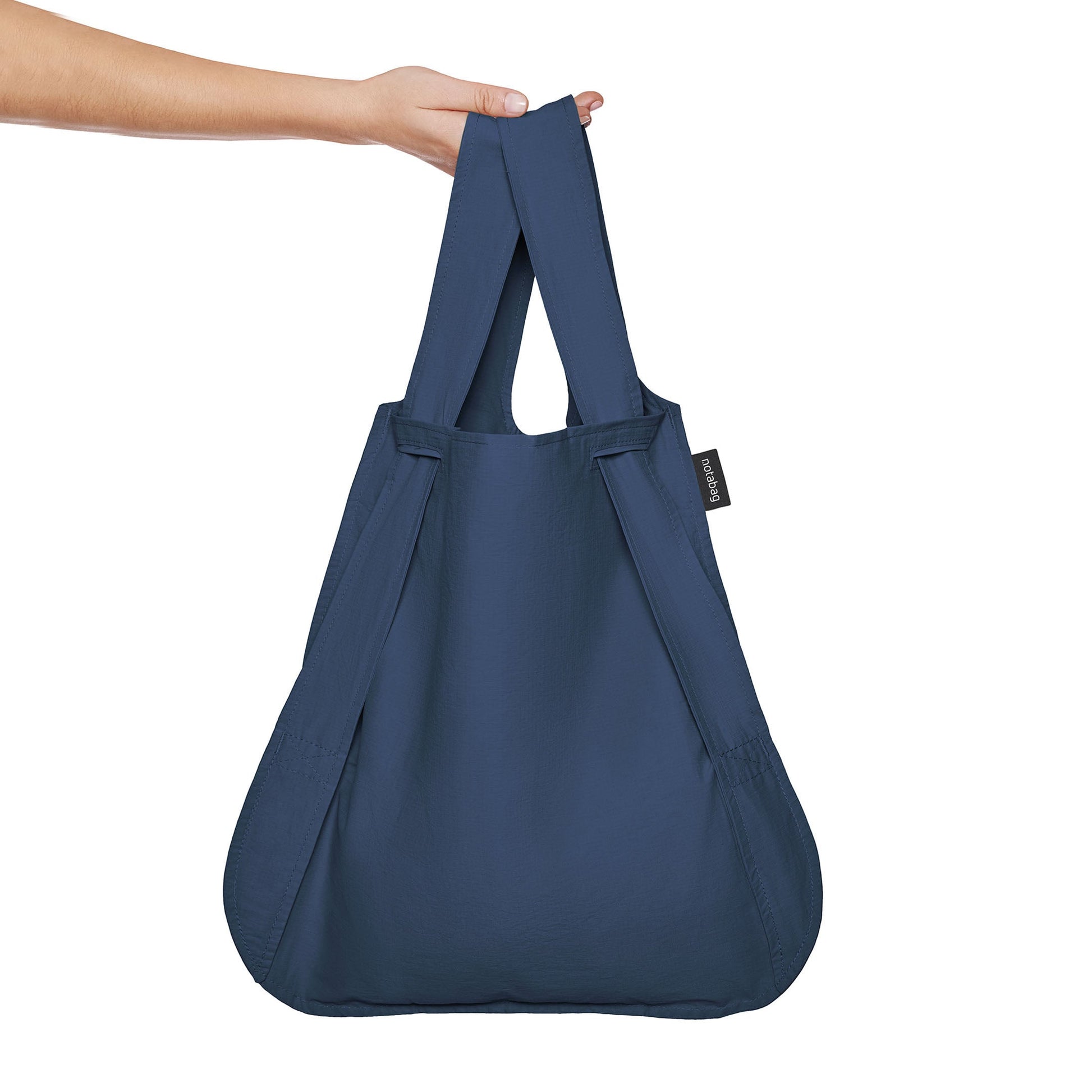 Navy blue Notabag as a shopper bag held in the hand