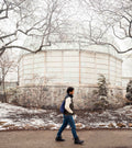 Man with navy blue Notabag backpack in front of a round building