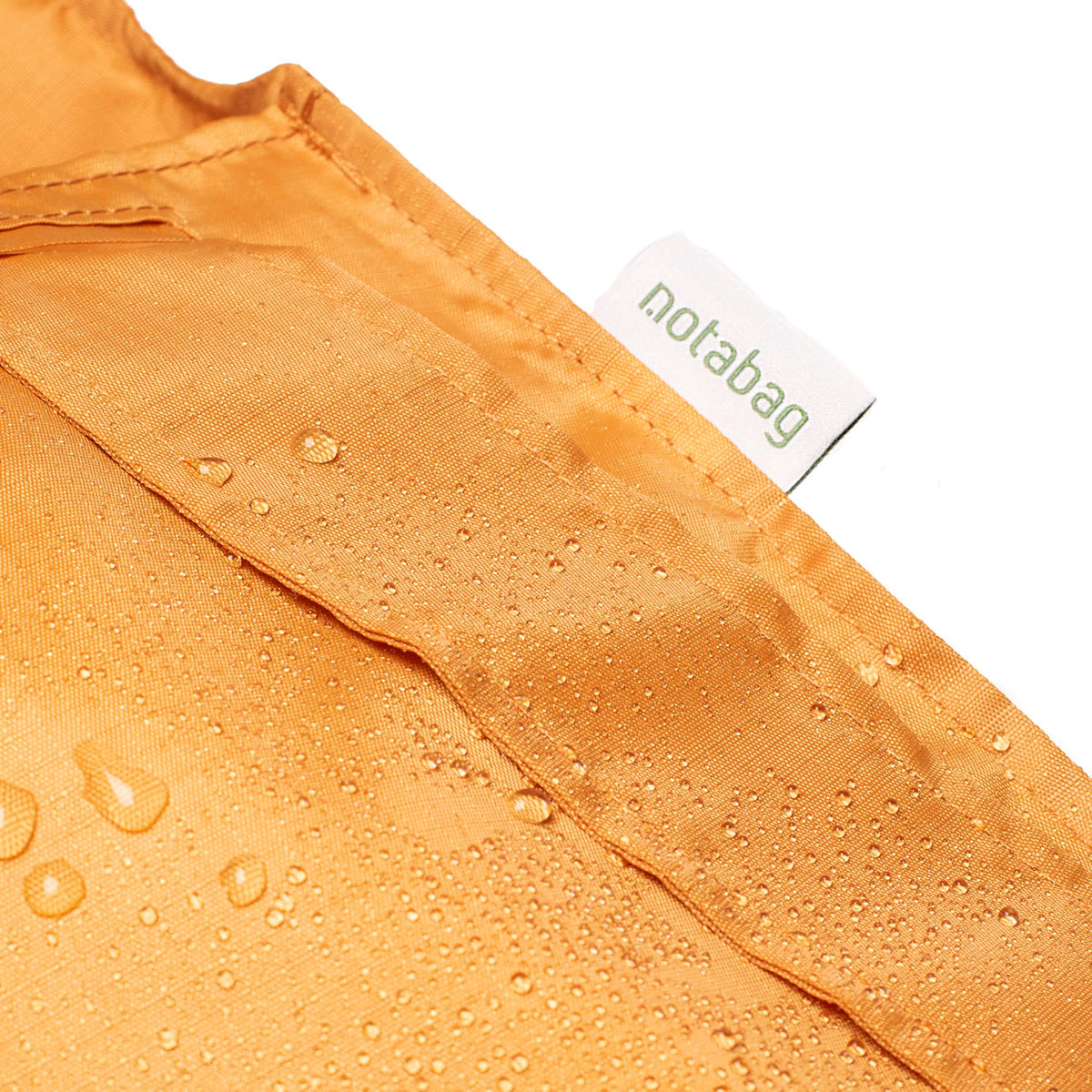 Detail van het waterafstotende label van Notabag Recycled Mosterd Geel