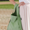 Vrouw draagt Notabag Olive shopper over de arm