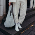 Vrouw met grijze Notabag shopper in de hand op een trap
