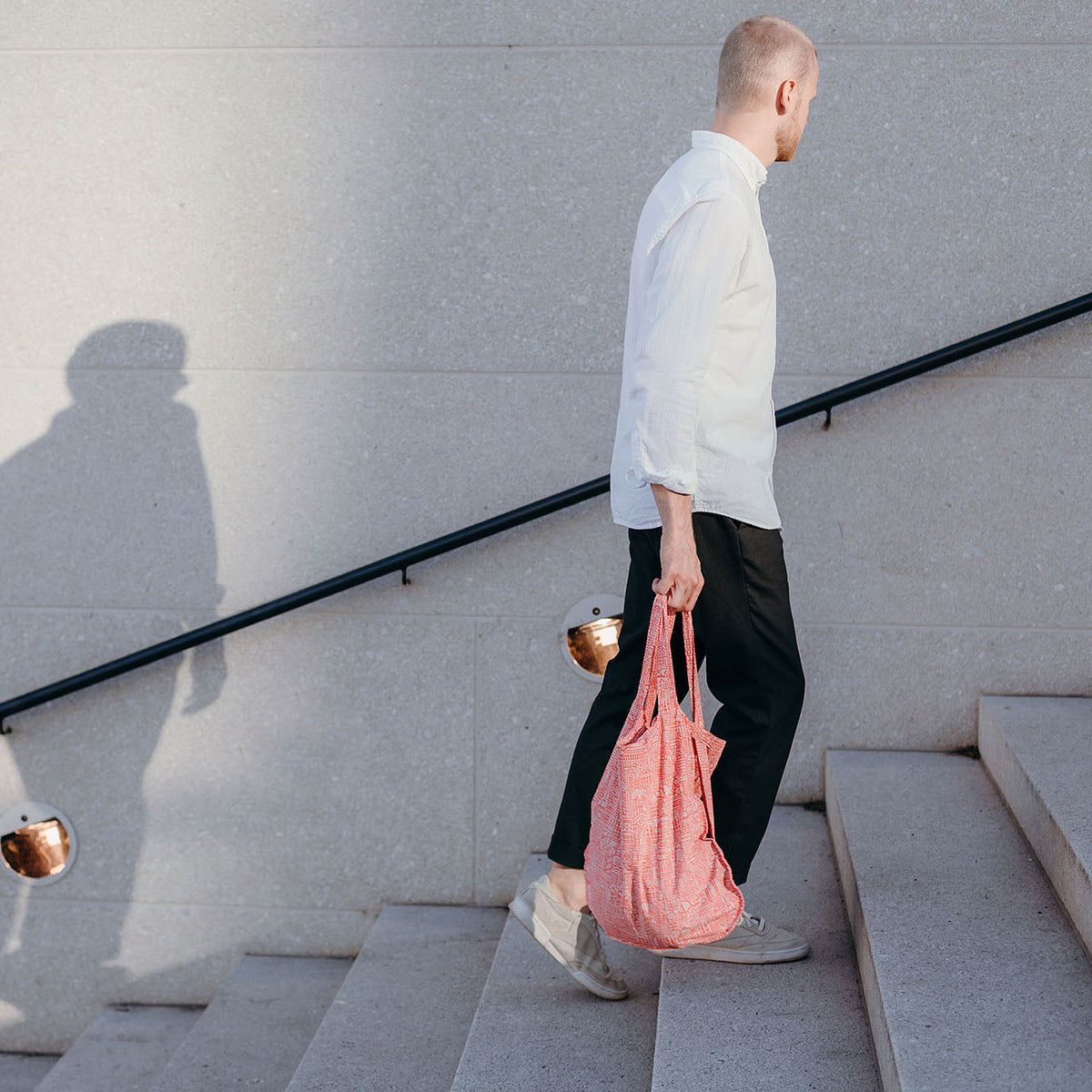 Man draagt Notabag Hello World Rose Red shopper op een trap buiten