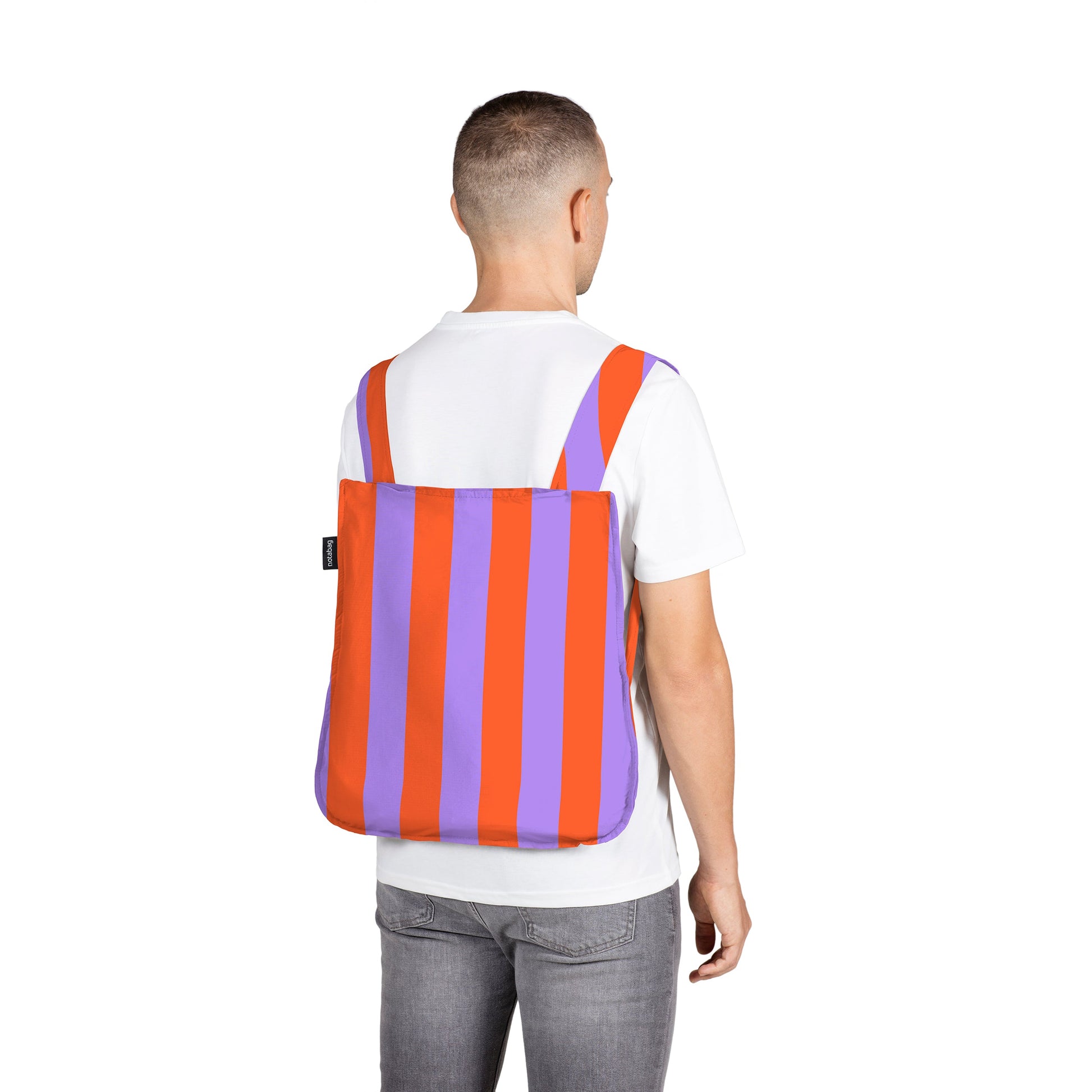 Man draagt Notabag Red & Purple Stripes rugzak tegen witte achtergrond
