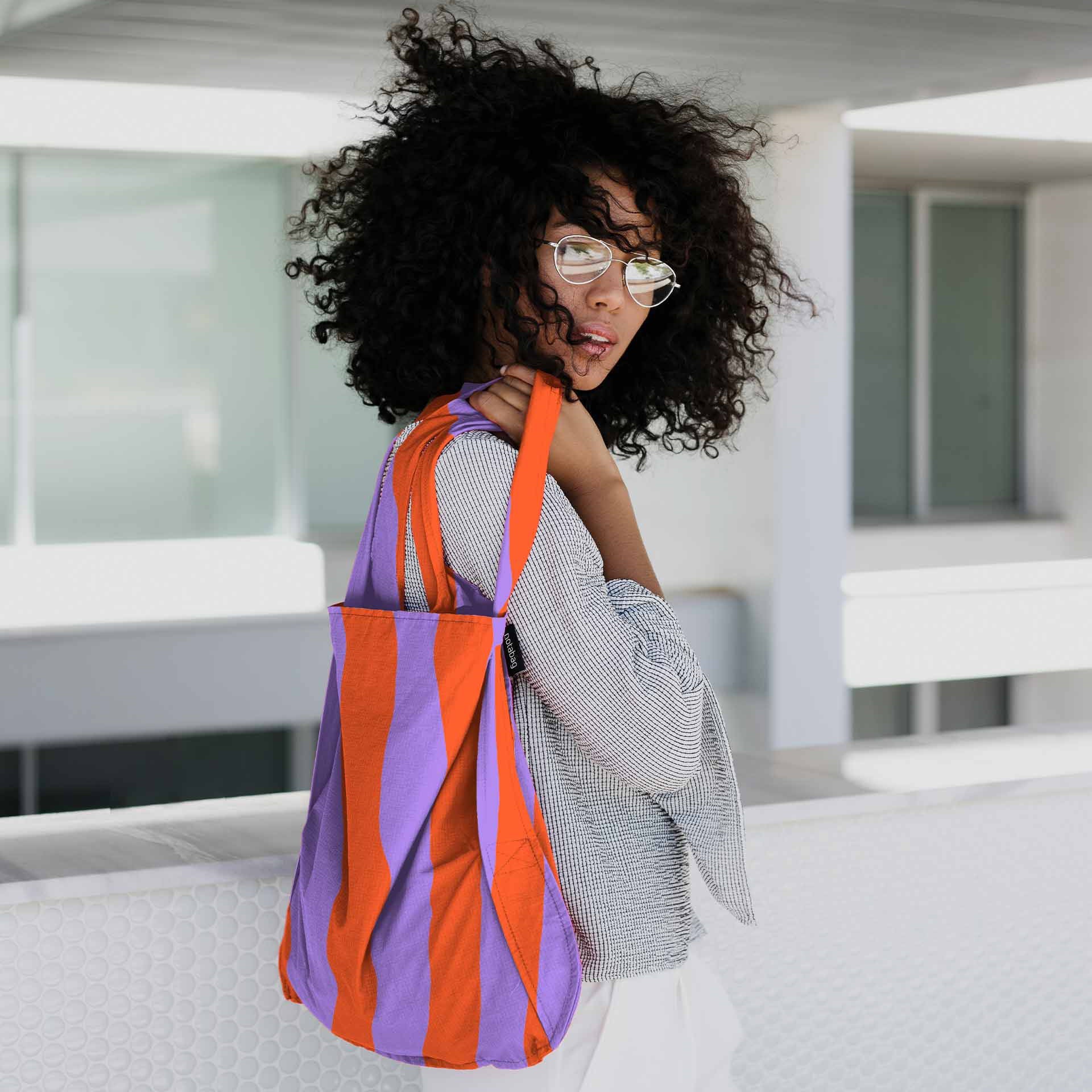 Vrouw draagt Notabag Red & Purple Stripes shopper over de schouder