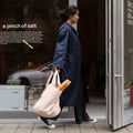 Frau trägt Notabag Sand Shopper-Tasche mit einem Baguette