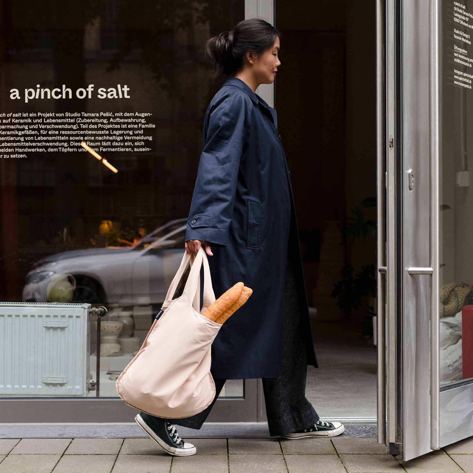 Frau trägt Notabag Sand Shopper-Tasche mit einem Baguette