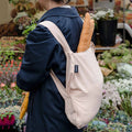 Frau trägt Notabag Sand Rucksack mit einem Baguette