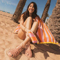 Woman on the beach with folded Notabag Vanilla Stripes