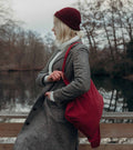 Vrouw met wijnrode Notabag shopper op een bruggetje bij een vijver