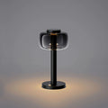 ELLE Decoration Odeon table lamp in matt black with the light on, against a grey background.