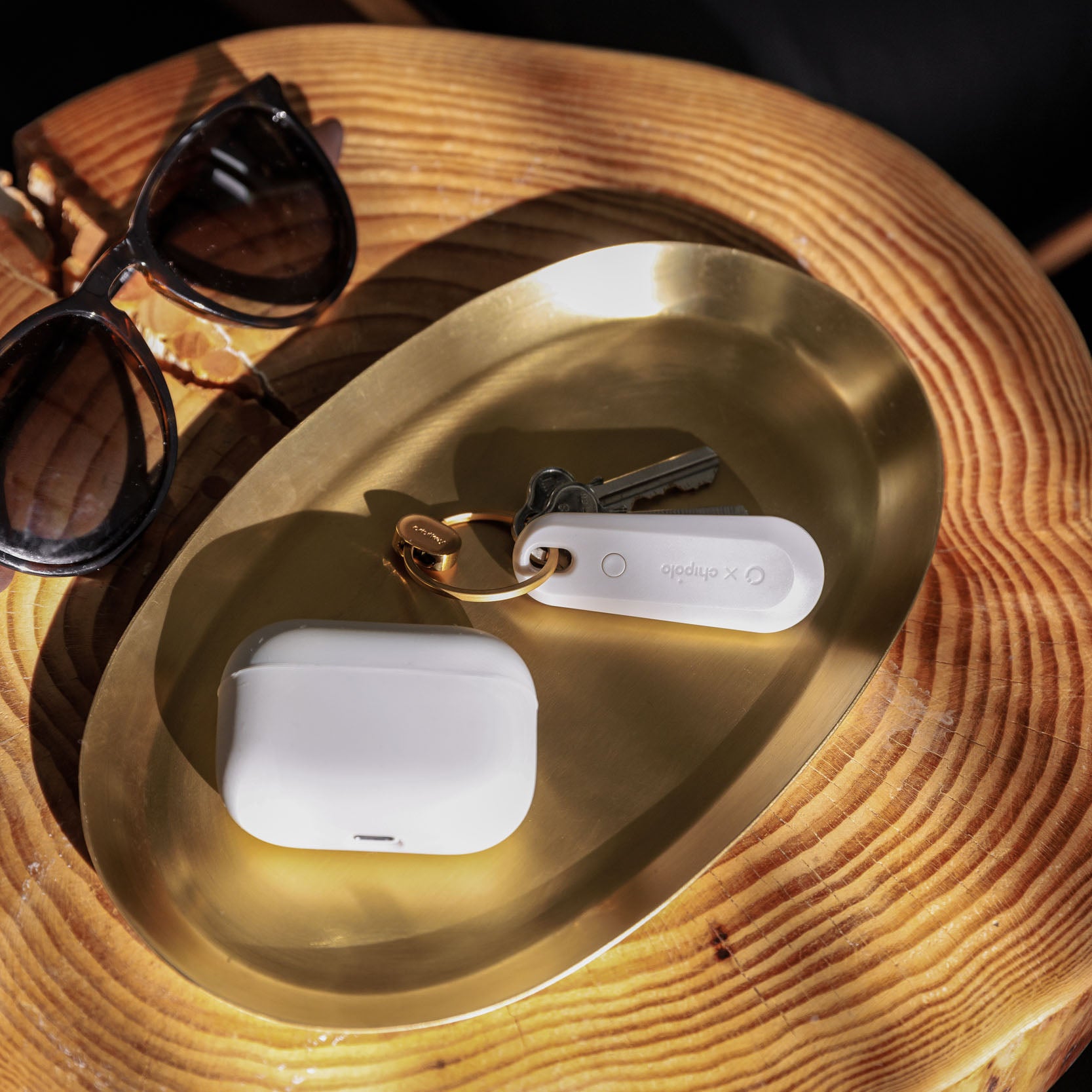 Orbitkey  Chipolo Tracker V2 Stone│art. TBT2-GRY-104│op koperen schaal naast earplugs