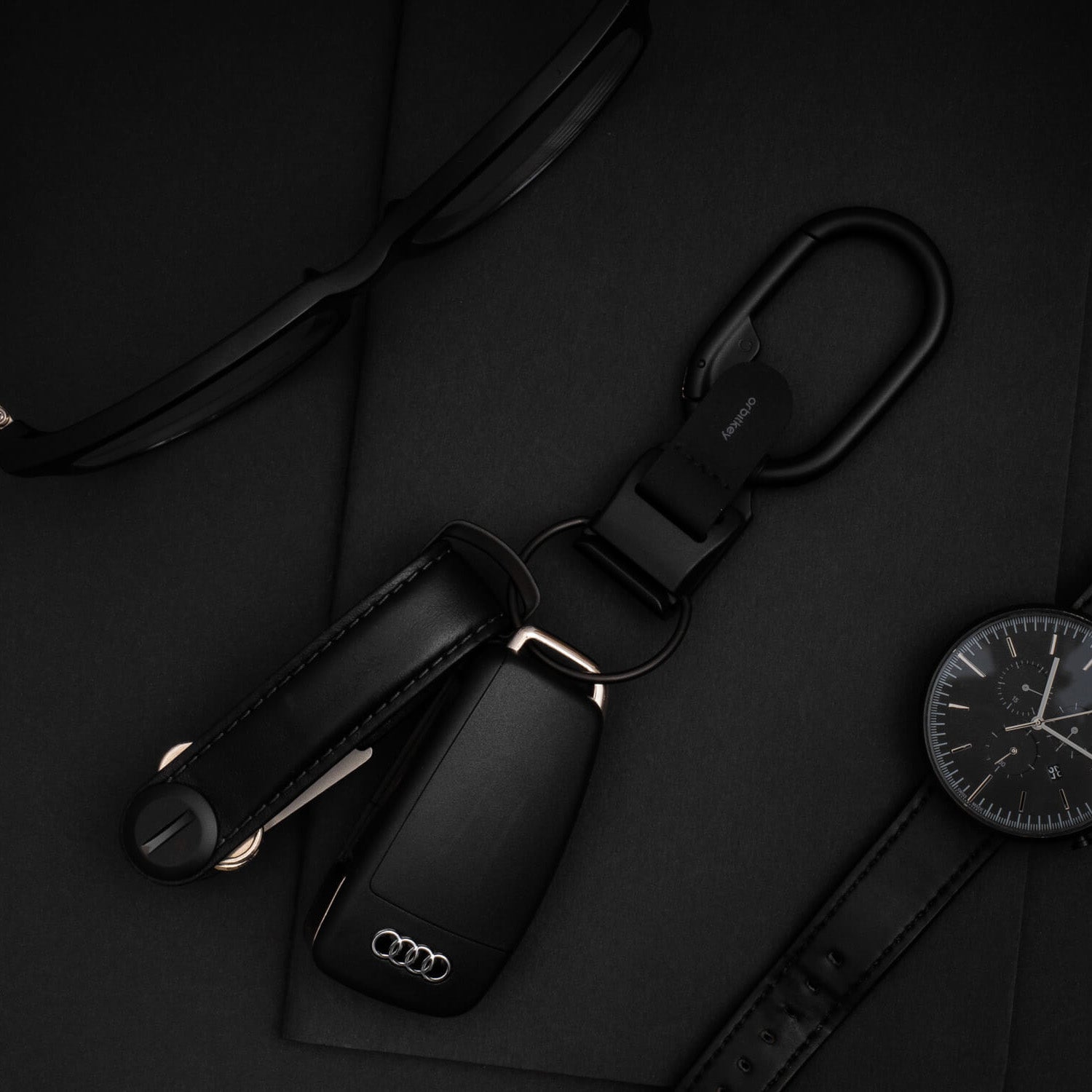 Orbitkey Clip V2 Zwart│art. CLPL-2-BKBKBK│met horloge en bril op zwarte ondergrond