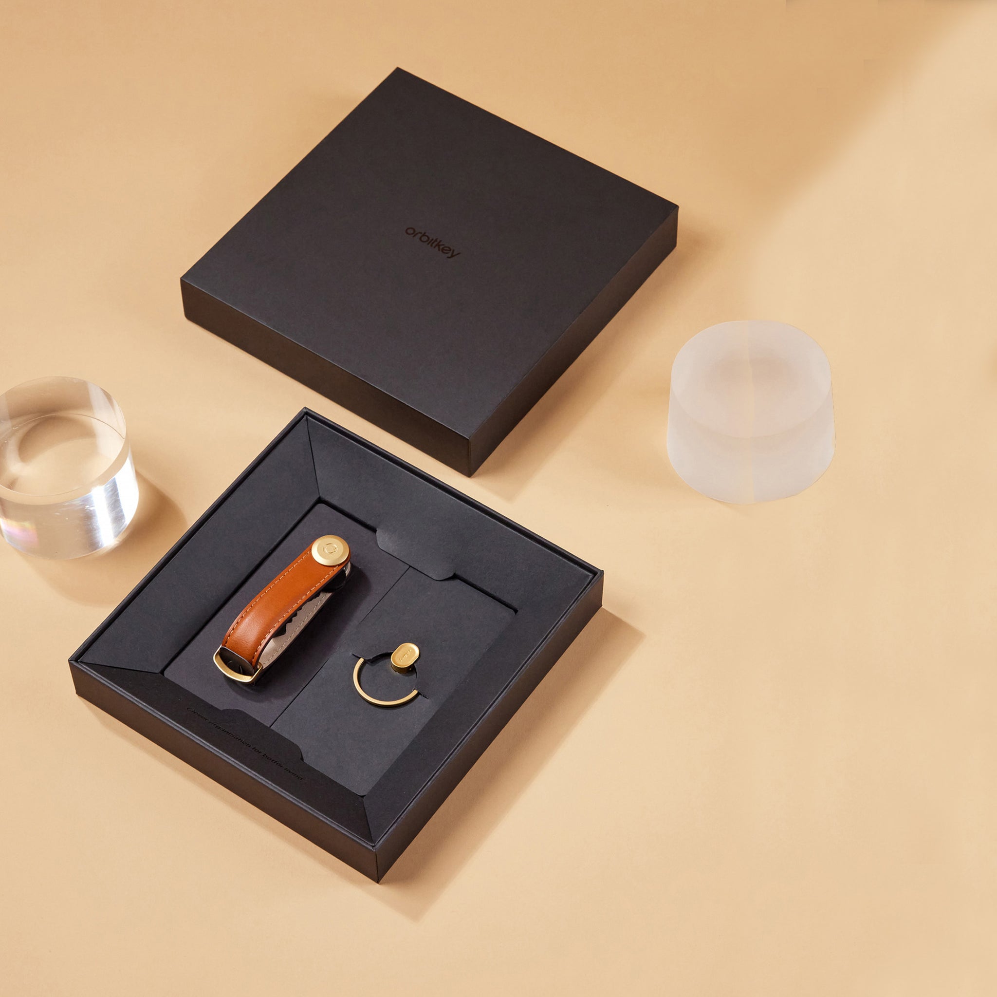 Orbitkey Gift Set Key Organiser Cognac-Tan+Ring V2 Gold│art. GLT2-CGT-201│in doos geopend naast glazen prisma