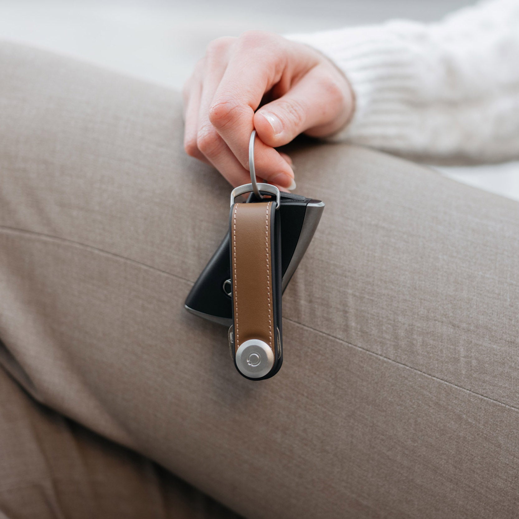 Orbitkey Sleutelhouder Hybrid Acorn│art. KHL3-ACN-111│vastgehouden door vrouw met hand leunend op been