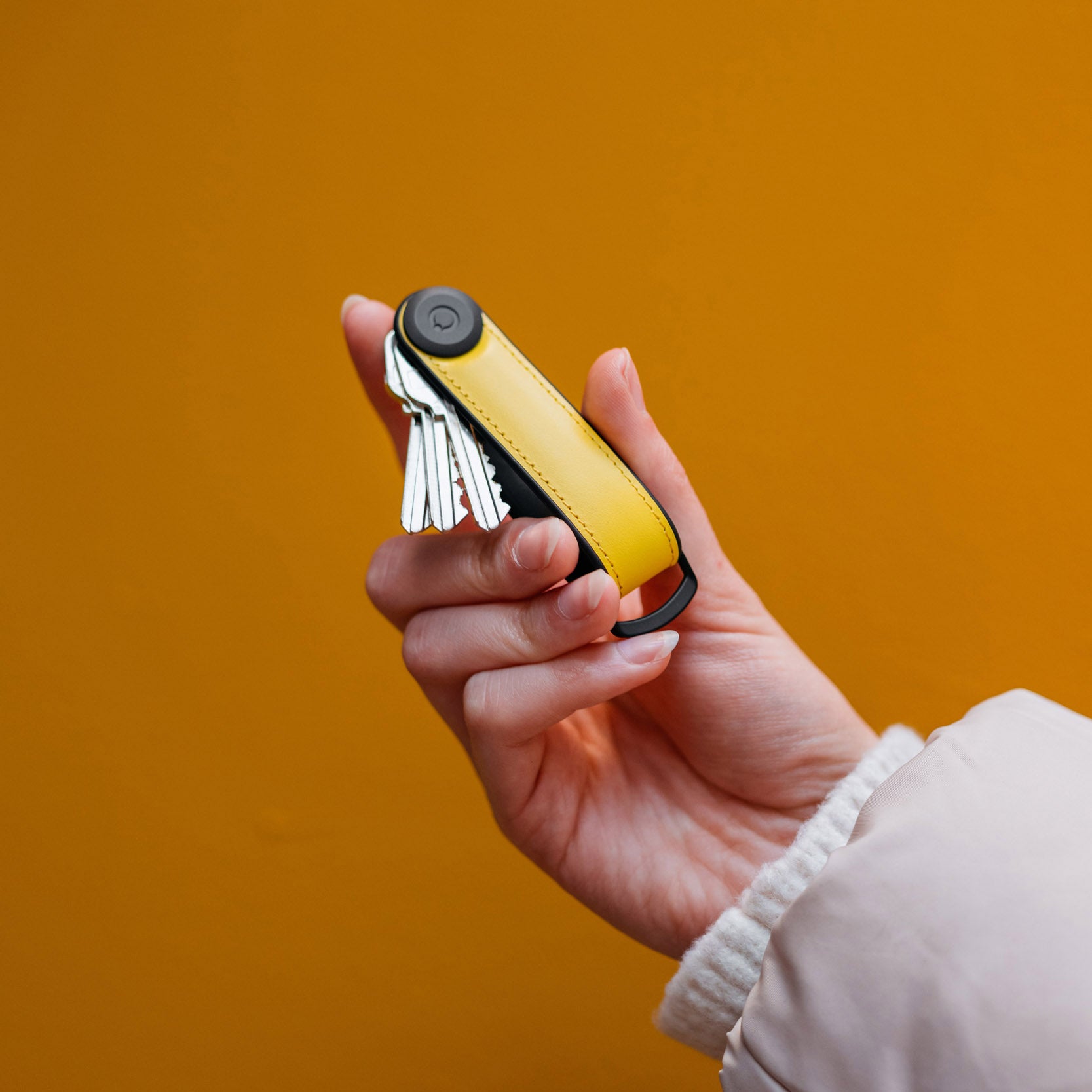 Key Organiser Orbitkey Hybrid Sun Yellow│art. KHL3-SYW-111│in hand met oranje achtergrond