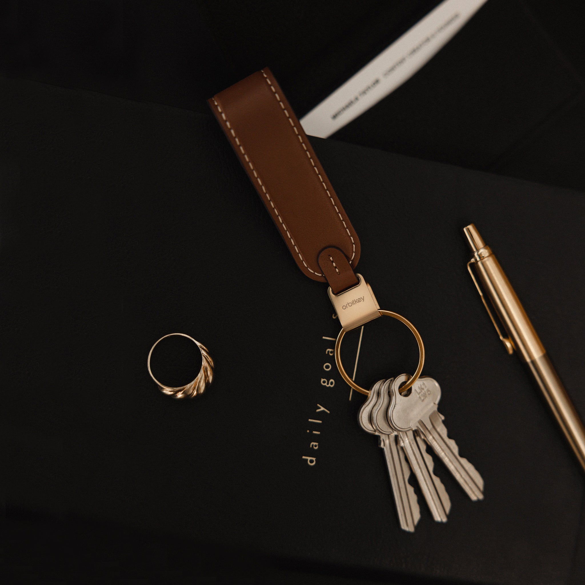 Orbitkey LoopZwart│Sleutelhange Leer│art. PLK1-BLK-101│liggend op agenda naast ring en gouden pen