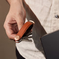 Orbitkey Pebbled Leather Amber│Sleutelhouder│art. KPB2-AMB-101│in hand met uitgevouwen sleutels naast laptop