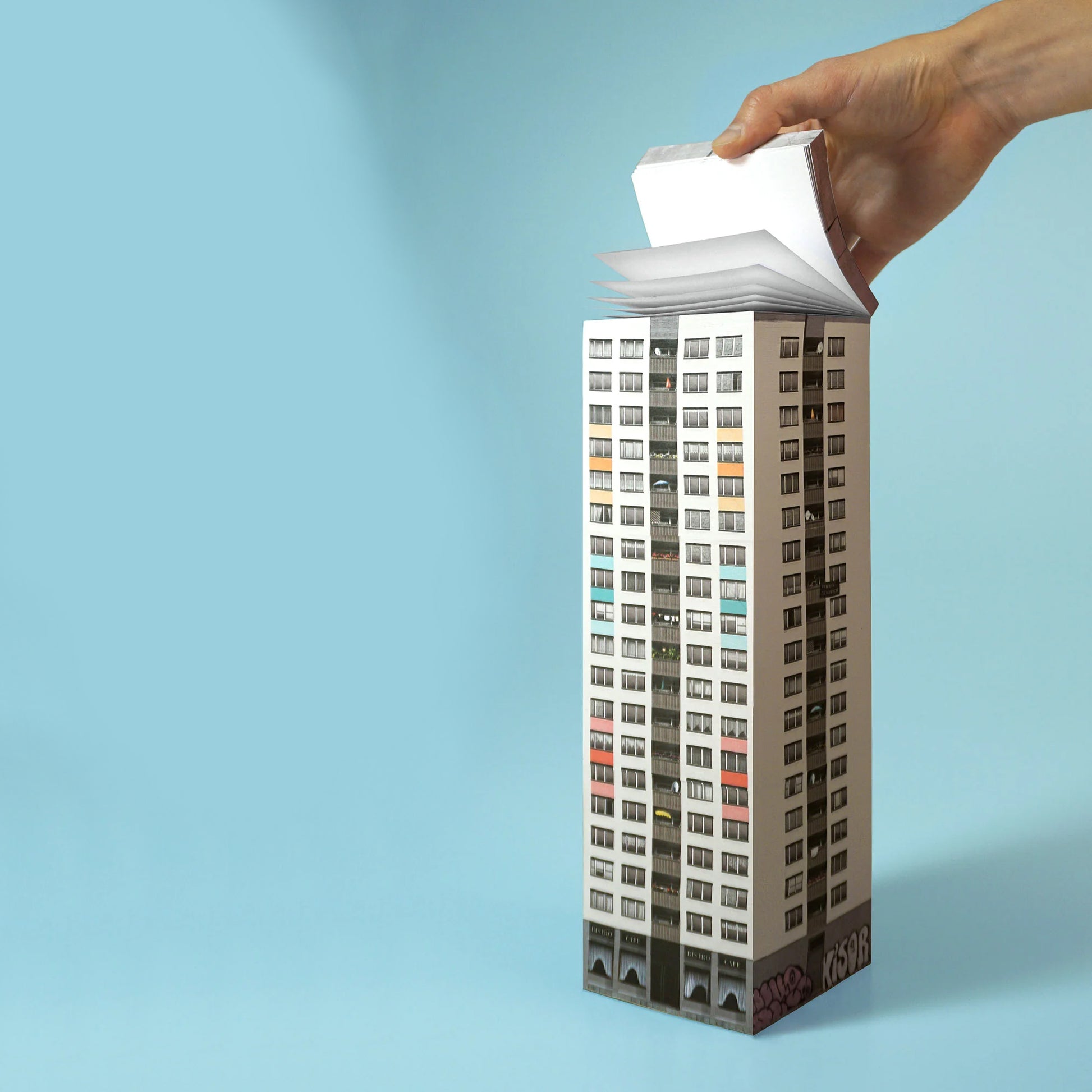 Paperscraper Plattenbau Berlin│Memoblok│vooraanzicht met hand aan losse blaadjes
