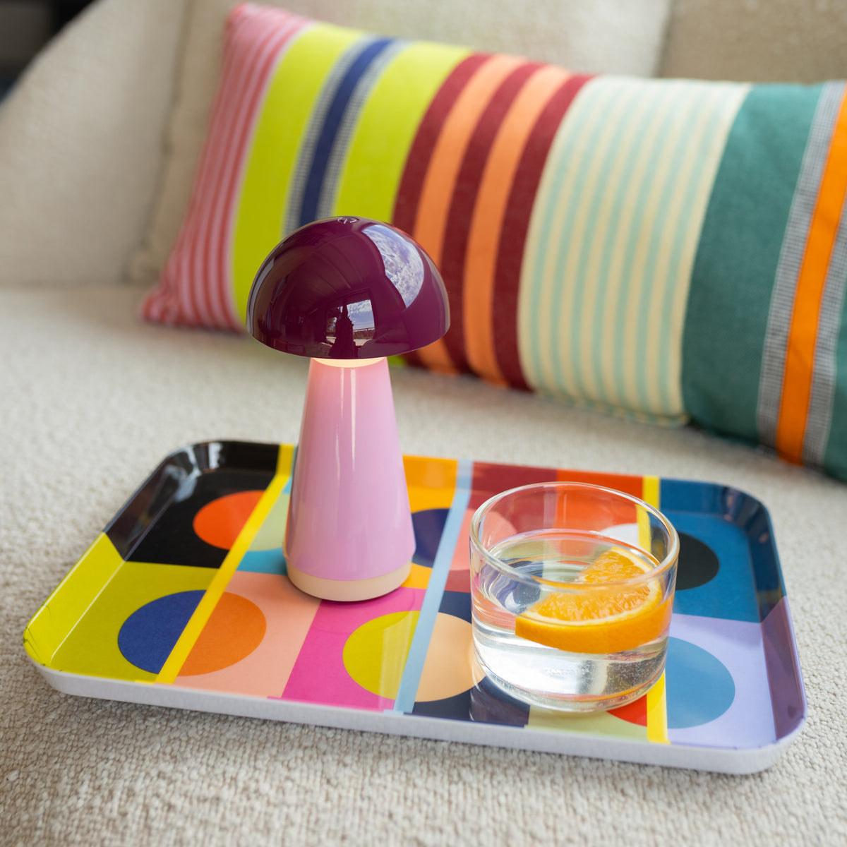 Remember Bobbi Oplaadbare LED Tafellamp | Berry | art. LB34 | op een dienblad met waterglas op een stoffen bank