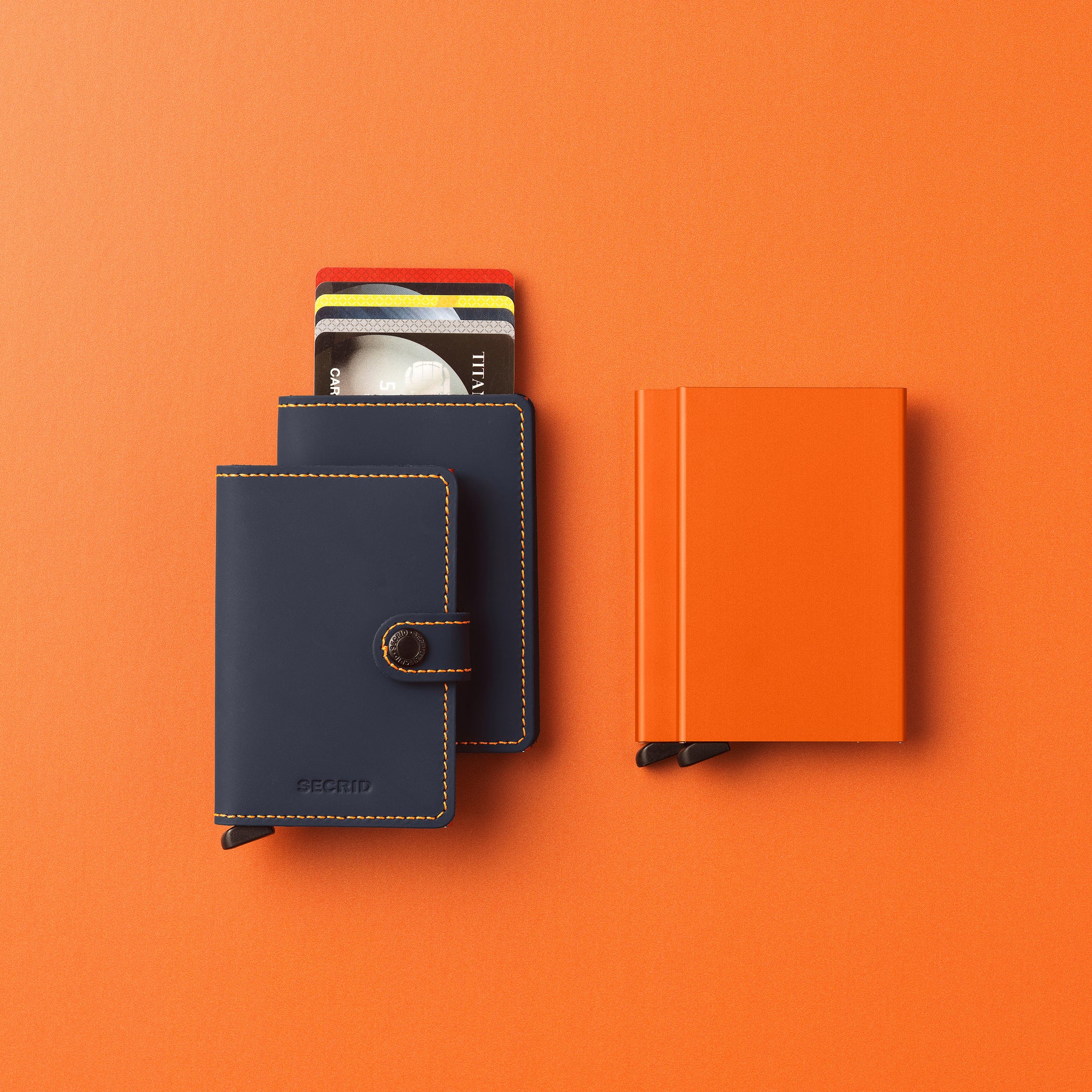 Secrid Miniwallet Matte│Pasjeshouder en Portemonnee│art. MM-NIGHTBLUE&ORANGE│met slimwallet en cardprotector op oranje ondergrond