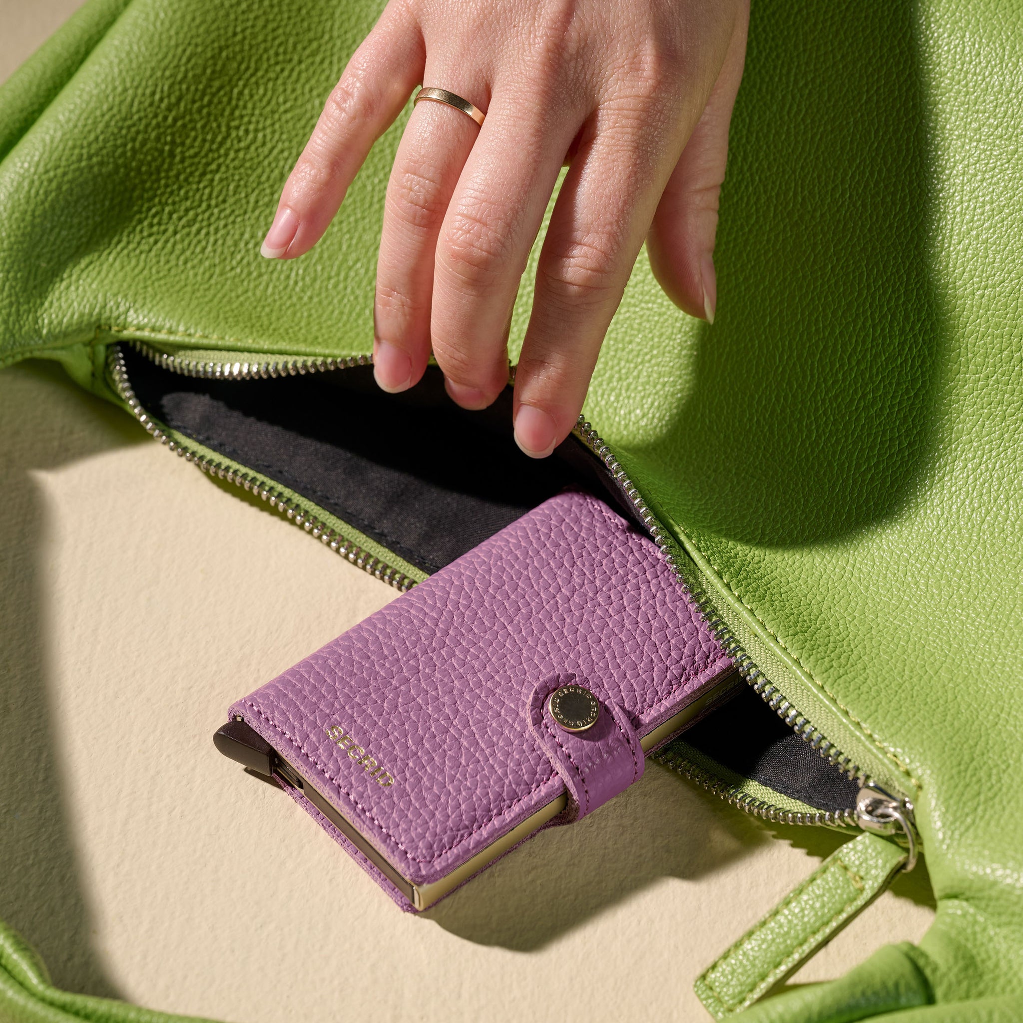 Secrid Miniwallet Pebble│art. MPE-ORCHID│Pasjeshouder│in groen tas met dameshand