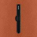 Secrid Miniwallet Veg│art. MVG-BLACK-BLACK│Pasjeshouder│zijaanzicht met caramello leer op achtergrond
