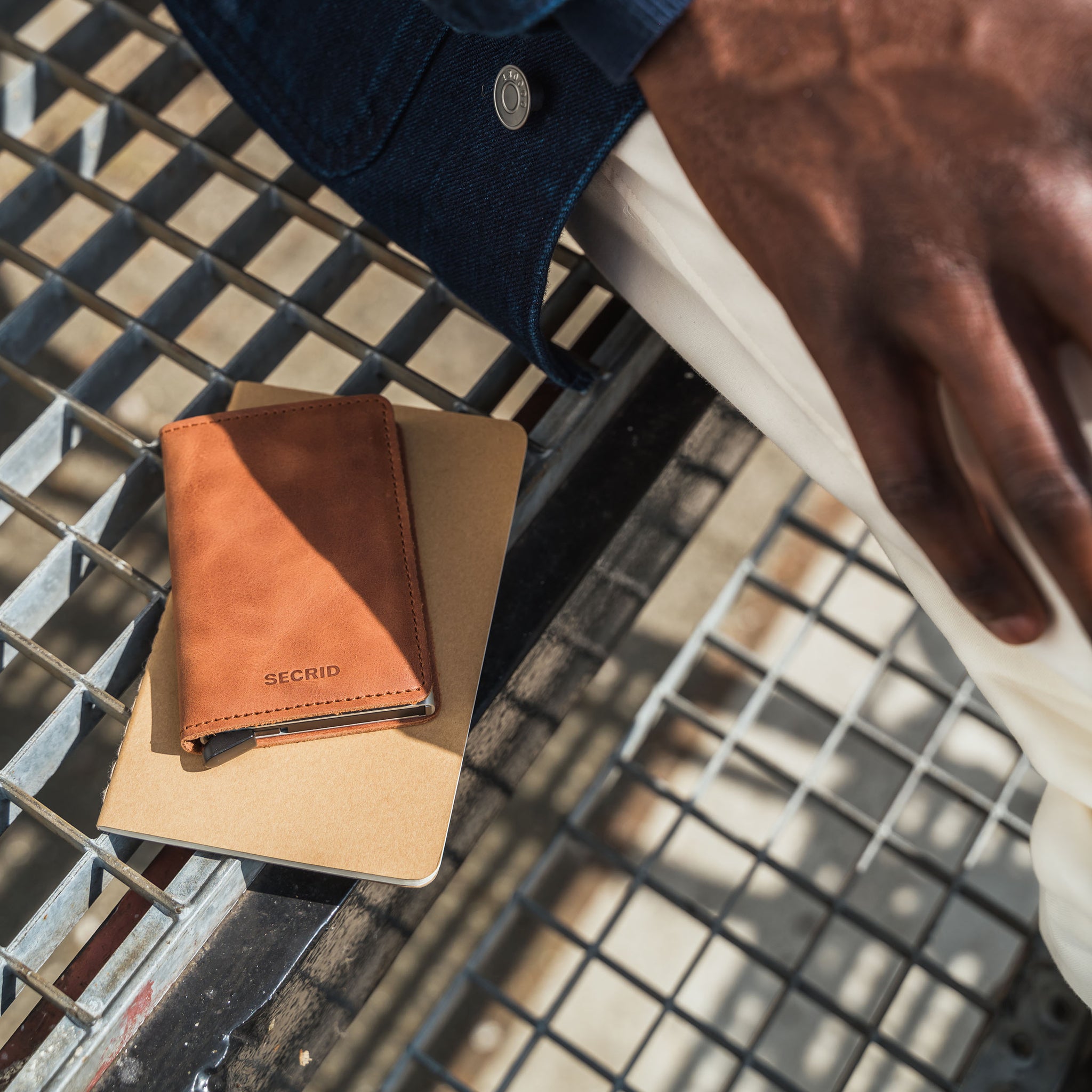 Secrid Slimwallet Vintage│Pasjeshouder│art. SV-COGNAC-SILVER│naast man op metalen rooster