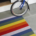 Chilewich Shag Deurmat 46x71 Pride Rainbow│art. 200872-001│close-up op tegelvloer naast fiets