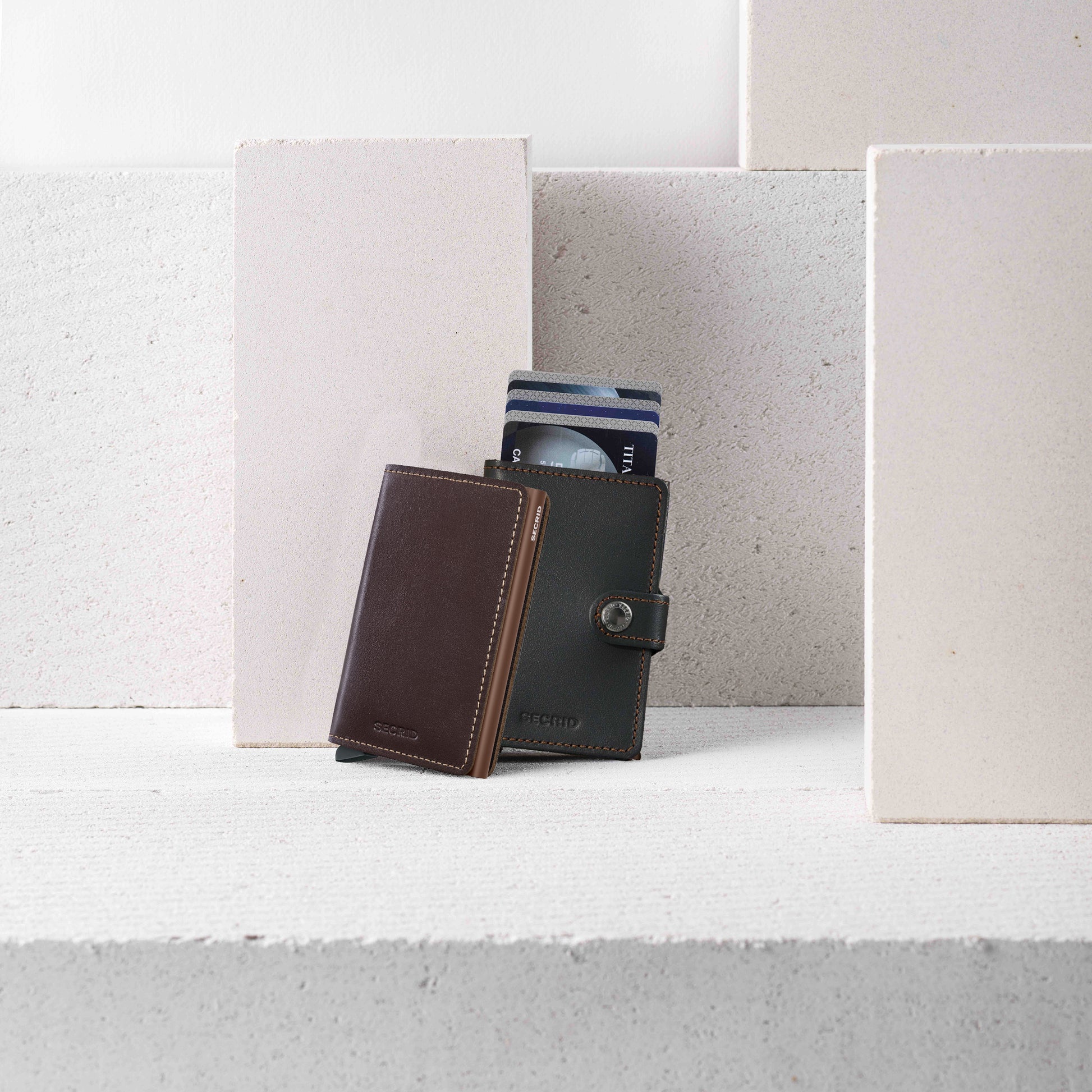 Secrid Slimwallet Original│art. SO-CHOCOLATE│leunend tegen Miniwallet met steenblokken op achtergrond