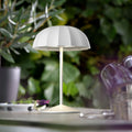 Sompex Ombrellino Oplaadbarer Buitenlamp│Wit│Tafellamp│art. 78351│op buitentafel met struiken op achtergrond