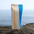 Strandlaken Martens & Martens Aqua Orange Purple & Yellow Suite702│art. CMMTT90AQORPUYE│voorkant vastgehouden op strand
