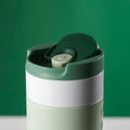 Dopper Travel Mug Small 300ml Forest Green - close-up van dop met geopende Flip Cap met groene achtergrond