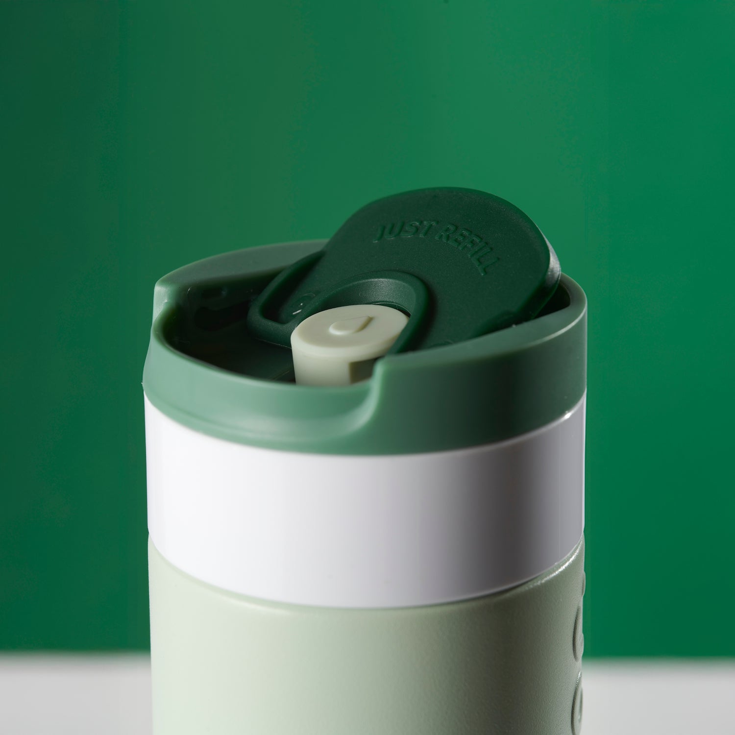 Dopper Travel Mug Small 300ml Forest Green - close-up van dop met geopende Flip Cap met groene achtergrond