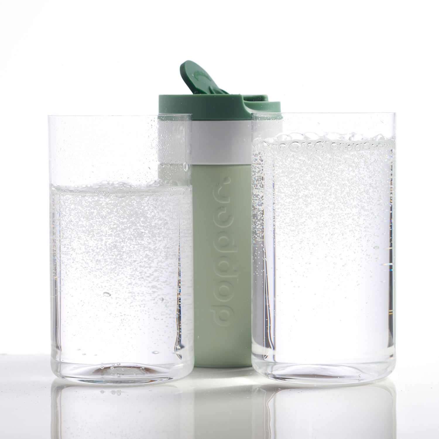 Dopper Travel Mug Small 300ml Forest Green - vooraanzicht met twee glazen op voorgrond met koolzuurhouden water
